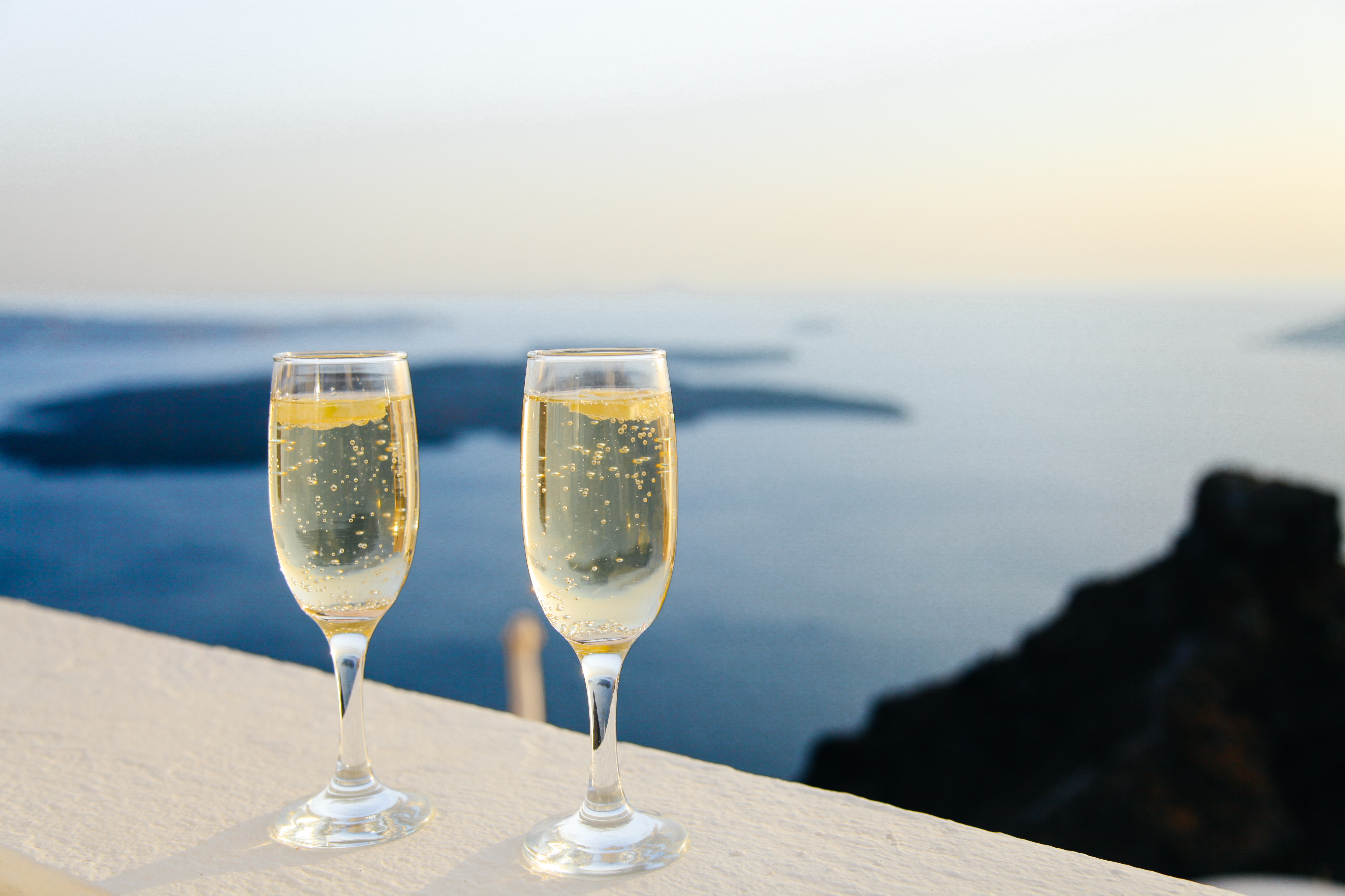 Two glasses of wine on a ledge overlooking the ocean