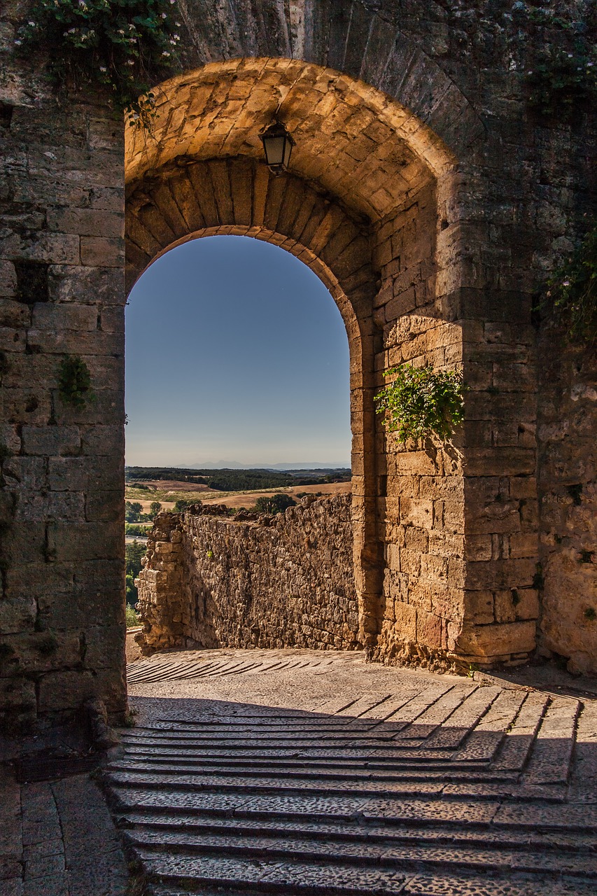 A stone-clad archway leading out on to a stone path in Monteriggioni