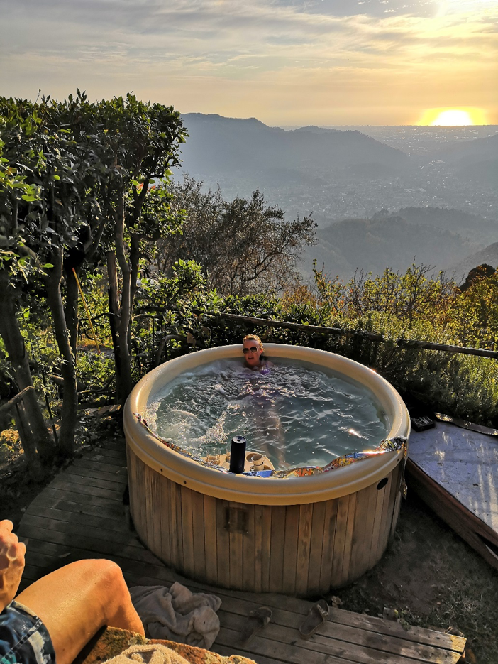 A man in a hot tub overlooking Tuscany at sunset