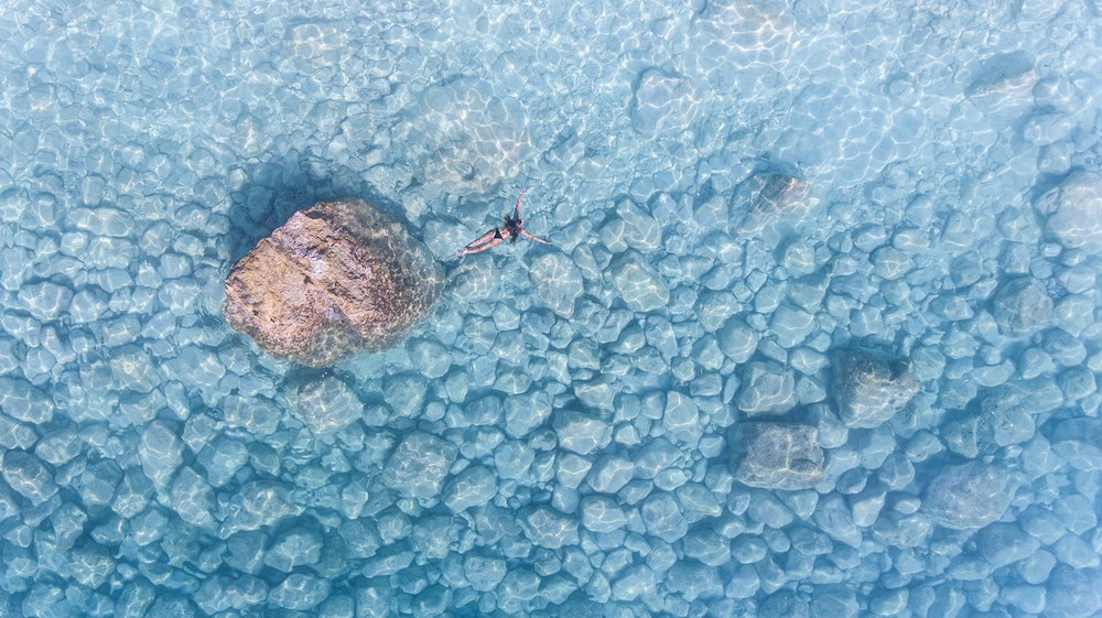 Woman swimming in turquoise, clear waters.