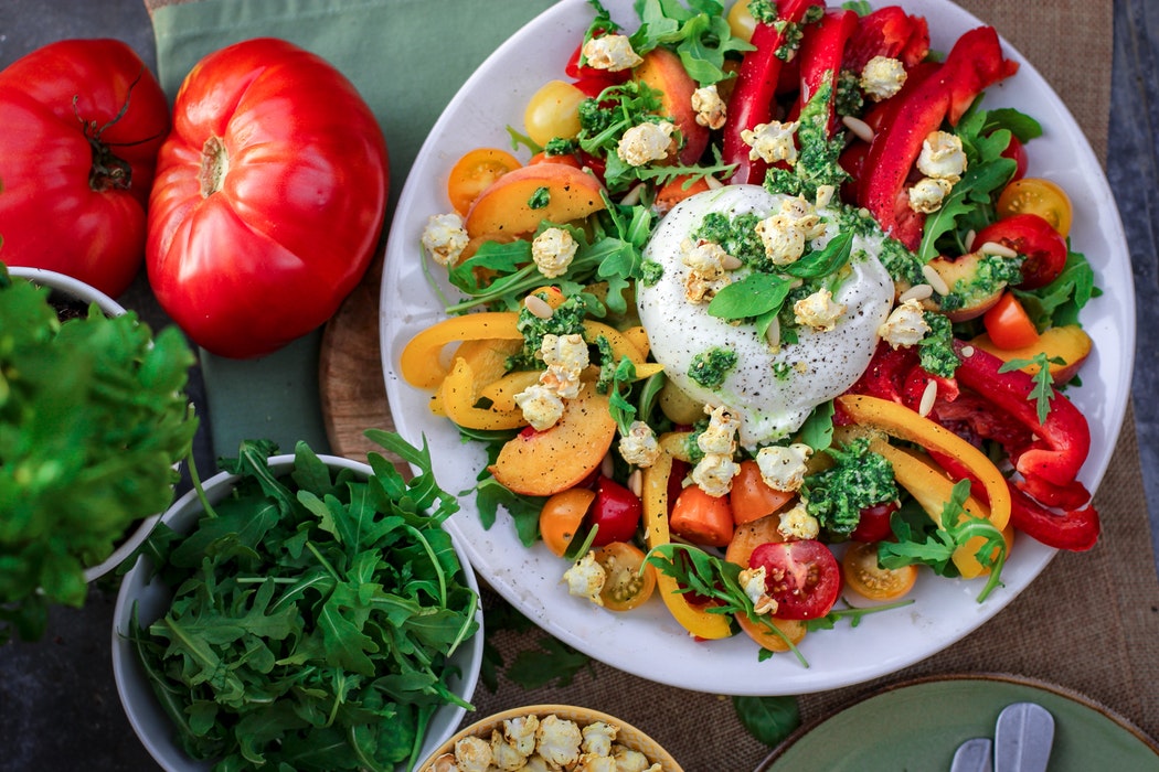 Burrata cheese ball on top of salad with coloured peppers