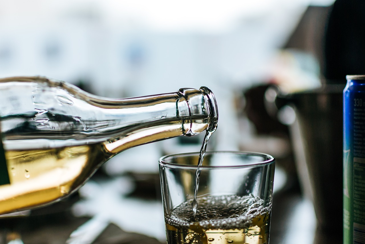 Bottle of white wine being poured into glass. 