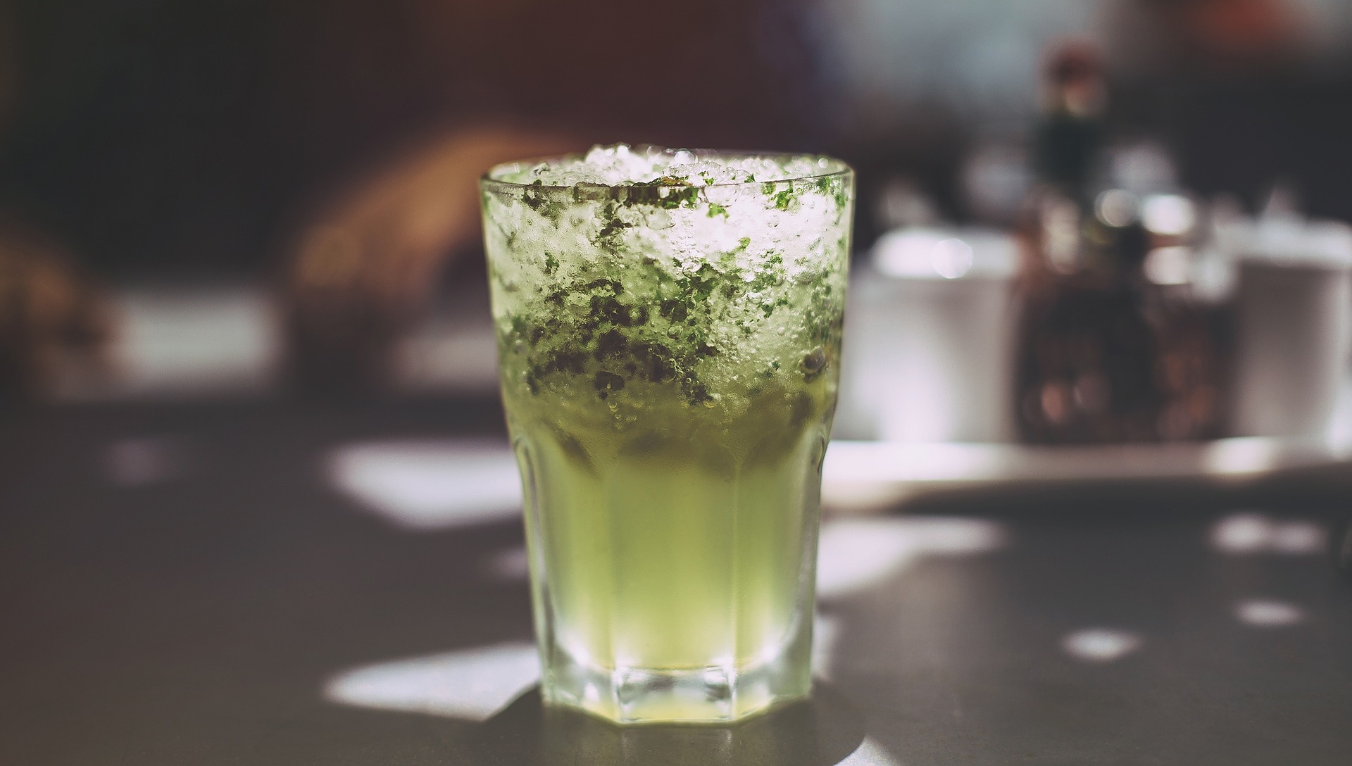 Green cocktail in clear glass with lots of ice. 